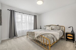 Primary bedroom, located upstairs, with a king bed, 55" Roku TV, closet, dresser, blackout curtains and a private ensuite full bathroom.