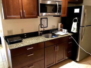 The kitchen has a coffee maker, induction cooktop, microwave, & full size fridge