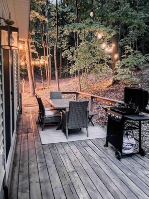 The back deck faces the forest and offers outdoor dining, a gas grill, and cozy string bulbs to set the evening mood.
