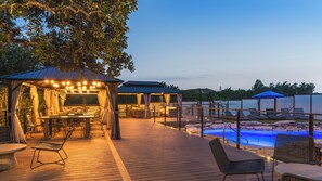 Serene outdoor oasis with elegant cabanas and a glowing pool—perfect for evening relaxation.