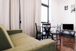Soggiorno elegante con divano letto, tavolo da pranzo.