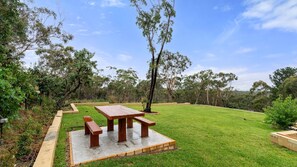Enjoy the peaceful view and unwind at the outdoor picnic table amidst lush greenery.