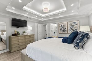 Primary bedroom with a comfortable king-size-bed, inviting decor, flat screen TV, a workspace, pool view and ensuite bathroom