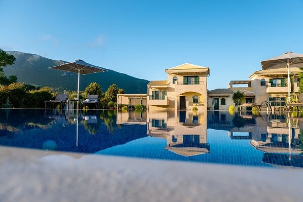 The pool area features comfortable sun loungers, cushions, and umbrellas, providing the perfect setting for relaxation.