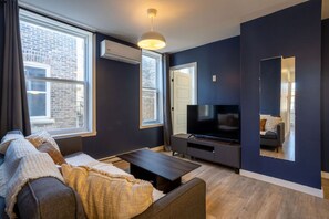 Spacious lounge area with wall-mounted TV, air conditioning, and natural light.