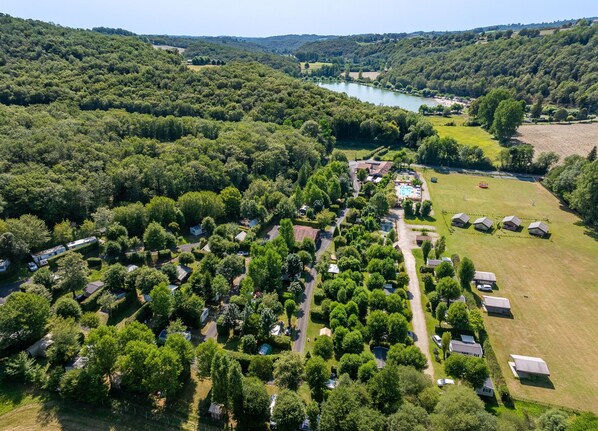 A breathtaking aerial view of the French countryside campsite, surrounded by lush greenery and a serene lake, perfect for a peaceful retreat.