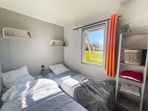 This cozy bedroom, filled with natural light and modern decor, invites family comfort with its inviting bedding and serene views.
