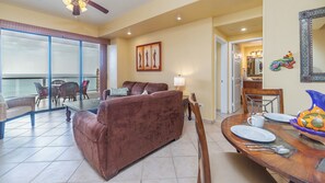 Full main room with dining area, living room set with inviting sofas. and direct balcony access.