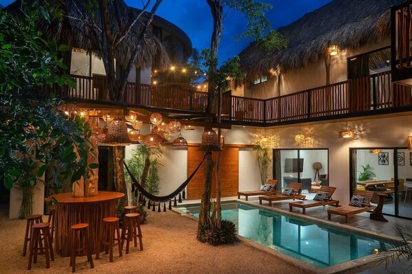 Incredible patio with a pool and an outdoor bar. Unique design that combines elegance with natural materials like bamboo and wood.