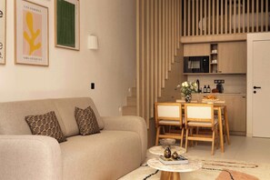 Salon avec canapé lit, TV, espace repas pour 4 personne et cuisine ouverte