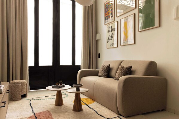 Salon avec canapé lit, TV, espace repas pour 4 personne et cuisine ouverte