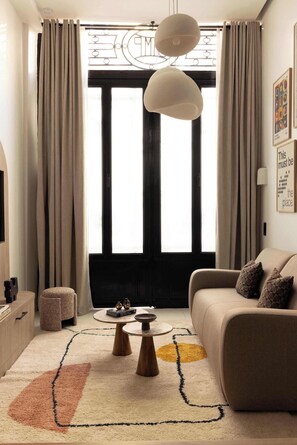 Salon avec canapé lit, TV, espace repas pour 4 personne et cuisine ouverte