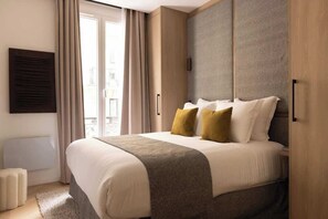 Une chambre parée d’un lit Queen size, d'une penderie, d'une TV et sa salle d'eau attenante équipée d'une douche et d'un lavabo.