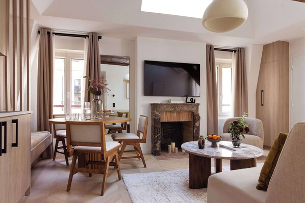 Une pièce à vivre dotée d'un canapé convertible, une TV, une table d'appoint et une table à manger pour 6 personnes. 