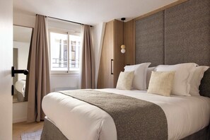  Une chambre parée d’un lit Queen Size, d'une penderie et d'une TV.