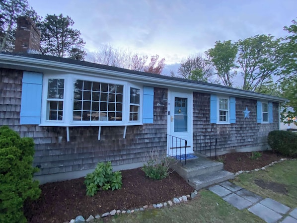 Classic Cape charm meets comfort – freshly mulched landscaping and coastal accents welcome you home after a day at the beach.