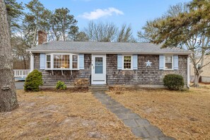 A classic coastal retreat with cedar shingles and light blue shutters, offering a warm and inviting atmosphere.