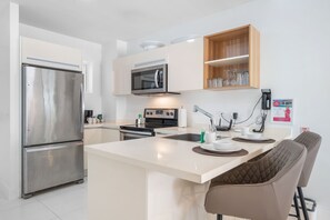 Open-concept kitchen with a spacious breakfast bar for casual dining - Fully equipped with modern appliances and essentials for a seamless cooking experience - Comfortable bar stools provide a perfect spot for morning coffee or evening drinks