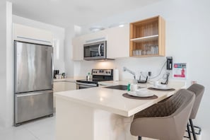Open-concept kitchen with a spacious breakfast bar for casual dining - Fully equipped with modern appliances and essentials for a seamless cooking experience - Comfortable bar stools provide a perfect spot for morning coffee or evening drinks