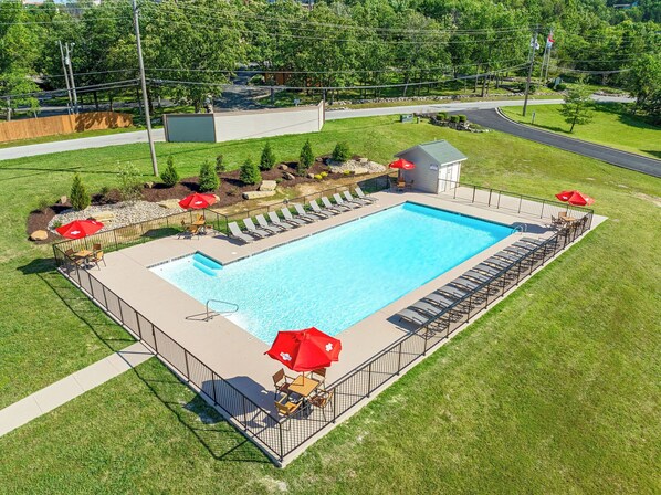 Communal pool with sunny loungers and red umbrellas, perfect for all day relaxation.