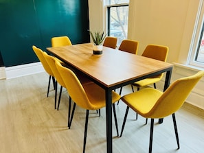 Host memorable gatherings in our stylish dining area at Jungle House Airbnb, featuring a sleek wooden table, vibrant yellow chairs, and a lush green accent wall 🌿 The perfect blend of modern elegance and cozy charm in Short North Columbus