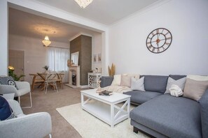 Enjoy this open-plan living and dining space featuring a comfy sectional sofa, modern decor, and a cozy dining area. Soft lighting and neutral tones create a warm, inviting atmosphere perfect for relaxing or entertaining.