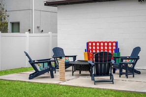 Backyard patio with Adirondack chairs, fire pit, and giant connect 4