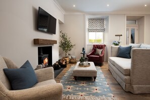 Coachman's Cottage - armchairs, a log burner and sofa in the living area