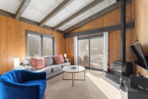Living area with a gas fireplace, flat-screen TV, and balcony access.