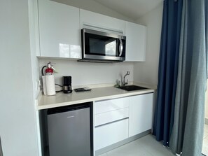 Whip up quick bites or enjoy a fresh brew in this sleek, fully stocked kitchenette - Compact yet efficient, featuring a microwave, mini-fridge, and coffee maker - Whether it’s a light breakfast or a late night snack, this space has you covered