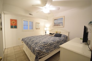 Primary bedroom with Queen bed, tile floors, ceiling fan, 32 in HDTV