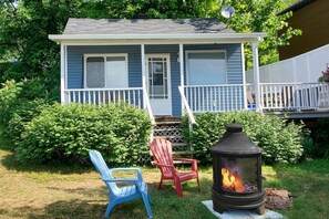 View of front of Cozy 1 with fire pit; deck and BBQ area are to right of cottage