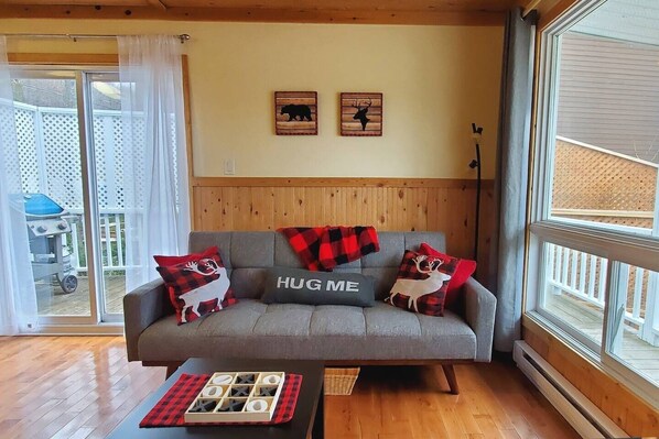 Seating area in living room with patio doors out to BBQ and  deck area