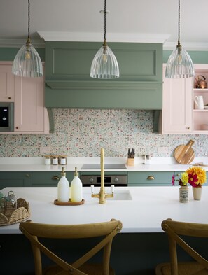 Stables Cottage - the colourful kitchen, decorated with whimsical floral tiles and brass fittings