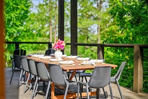 Spacious outdoor dining table set against lush forest backdrops.