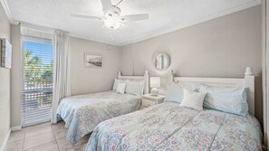 This cheerful guest bedroom features two full-size beds, coastal-themed bedding, and plenty of natural light. It's the perfect setup for kids or friends to unwind after a day at the beach.