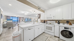 Cook with ease in this bright, fully equipped kitchen featuring white cabinetry, full-size appliances, and an in-unit washer/dryer. Enjoy Gulf views thanks to the open layout connecting to the living area.