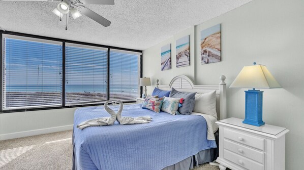 Wake up to breathtaking beach views from this bright and airy primary bedroom. Large picture windows fill the space with natural light and frame the Gulf's sparkling blue waters. The king bed is dressed in tranquil ocean tones, accented with coastal artwo
