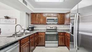 This fully equipped kitchen features stainless steel appliances, granite countertops, and rich wood cabinetry. It’s perfect for preparing meals with ease during your beachfront getaway.