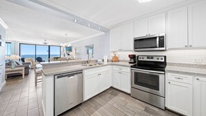 Fully equipped kitchen with stainless steel appliances and view of the dining and living areas.