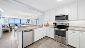 Fully equipped kitchen with stainless steel appliances and view of the dining and living areas.