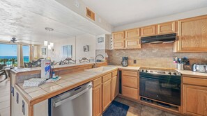 Fully equipped kitchen, with dishwasher, dining area, view of the living room.