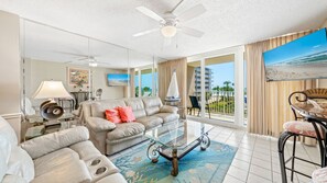 Living Room with a View – Relax in a spacious, light-filled living room featuring plush leather seating, a large TV, and direct access to the balcony overlooking the Gulf.