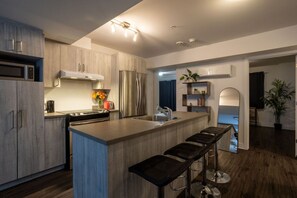 Fully equipped modern kitchen with stainless steel appliances, a large island, and breakfast bar seating.