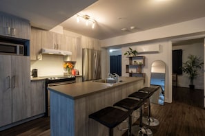Fully equipped modern kitchen with stainless steel appliances, a large island, and breakfast bar seating.