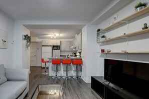 Bright and inviting living area with contemporary décor, bold red bar stools, and a fully stocked kitchen in the background – a perfect blend of comfort and style