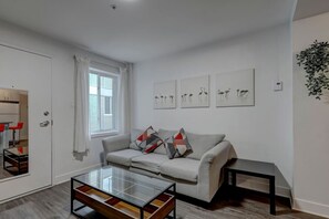 Cozy and well-lit lounge area with a plush sofa, artistic wall décor, and a coffee table for relaxed evenings or social gatherings