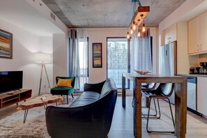 A cozy and contemporary setting featuring a sleek seating area, rustic wood dining table, and industrial-inspired lighting.