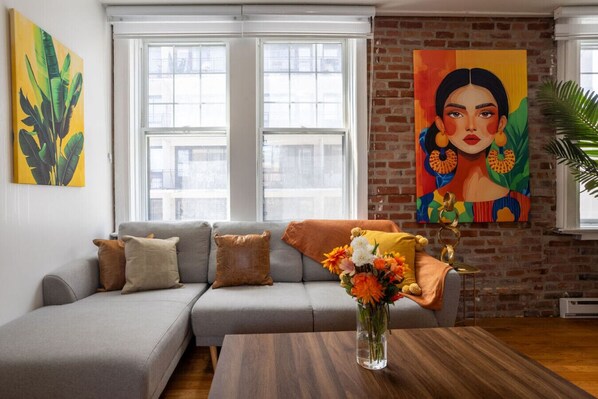 This sun-filled living room welcomes you with warm tones, layered textures, and art that energizes the whole space