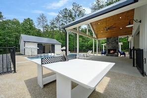 Luxury outdoor retreat with ping pong, a cozy fireplace, and a private pool.